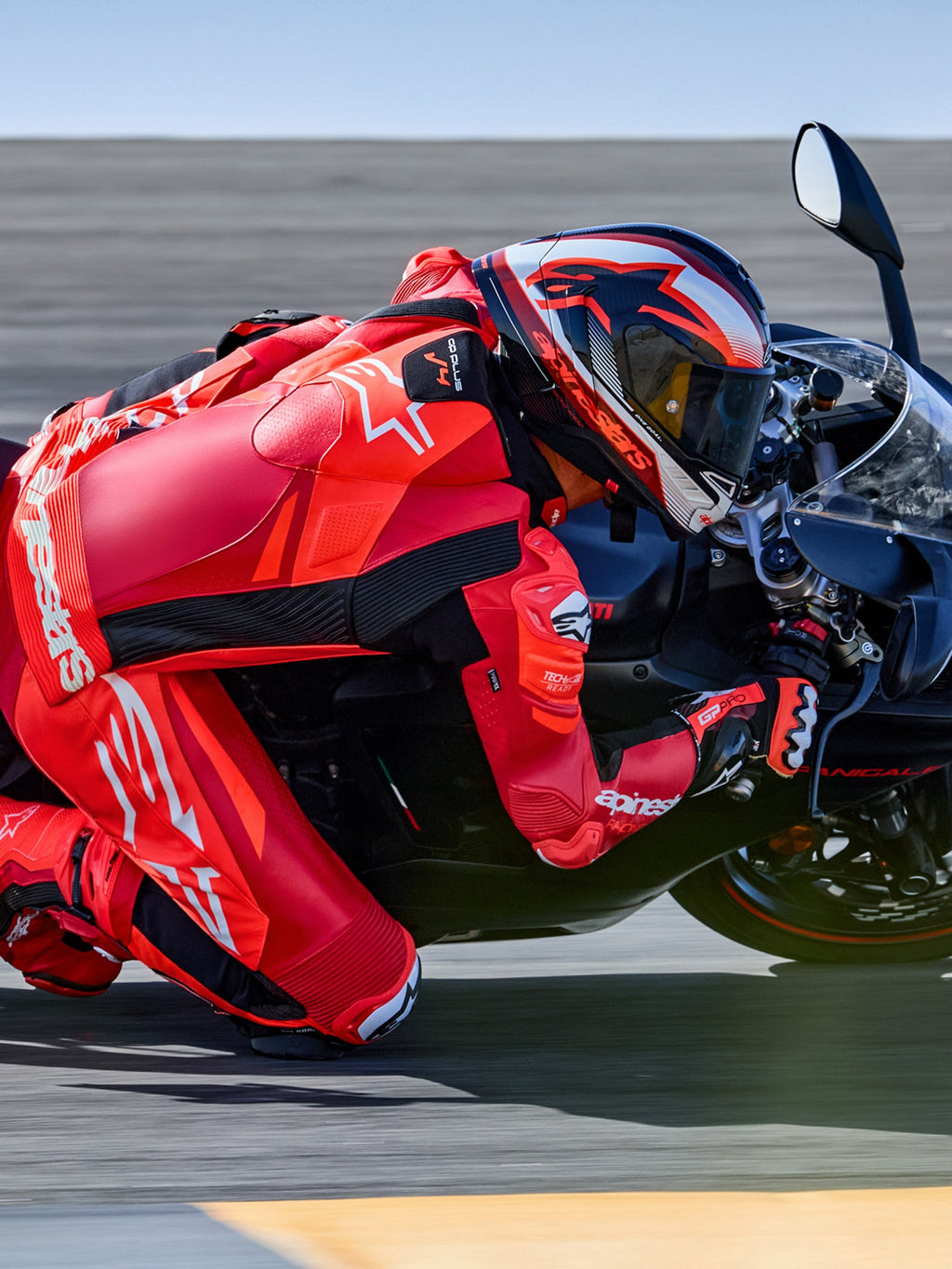 Alpinestars GP Plus V4 Sprint skinnställ 1-styck, röd fluo och vit, Tech-Air-redo racingoverall på förare i en kurva på banan.
