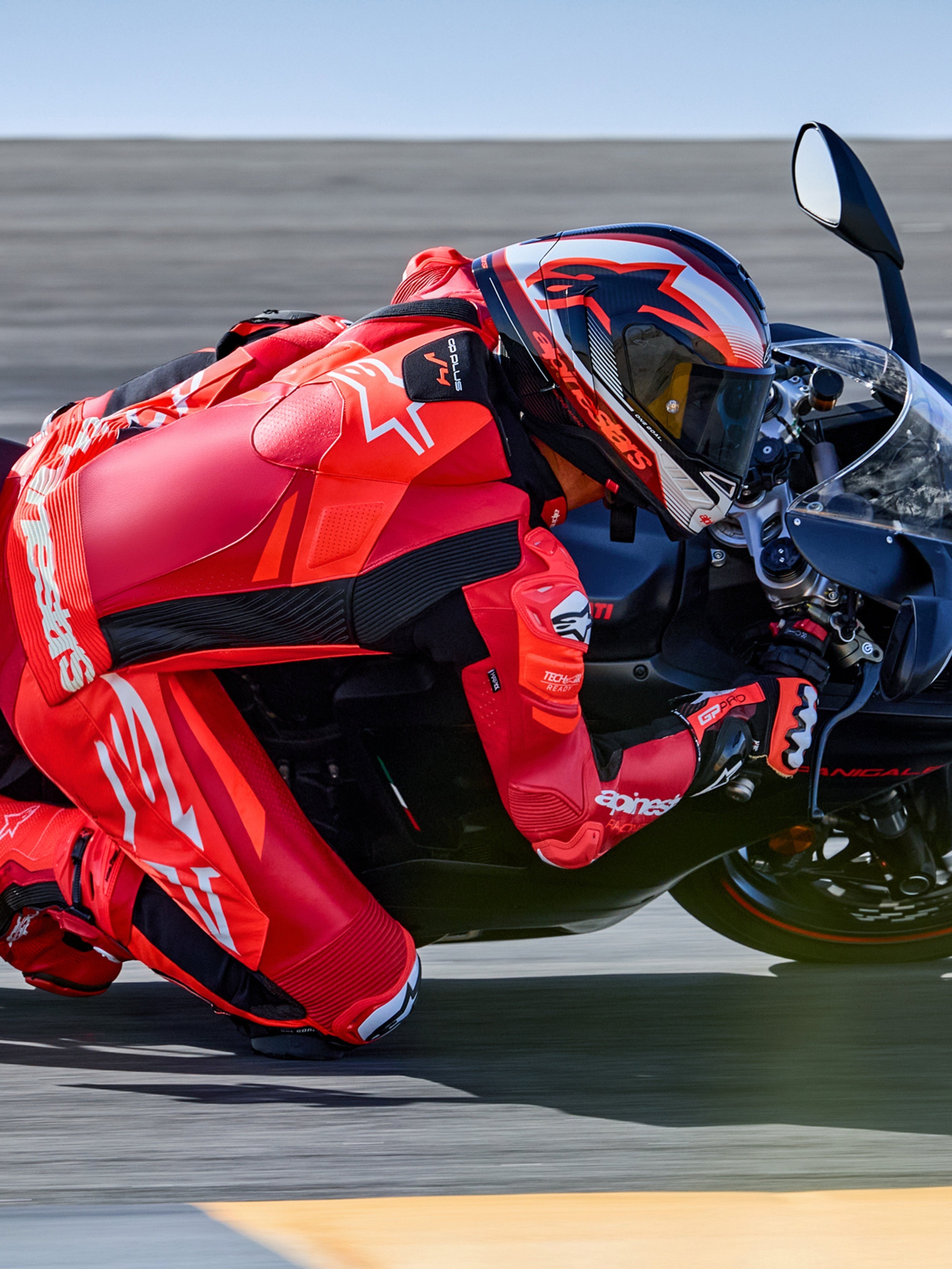 Alpinestars GP Plus V4 Sprint skinnställ 1-styck, röd fluo och vit, Tech-Air-redo racingoverall på förare i en kurva på banan.