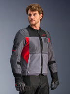 Alpinestars St-2 Air Jacket, Motorcycle Riding Jacket, Deep Gray and Dark Gray with Bright Red accents, featuring large mesh ventilation panels, laser-perforated details, and red star logo, worn by a model in a studio setting, modern adventure touring style