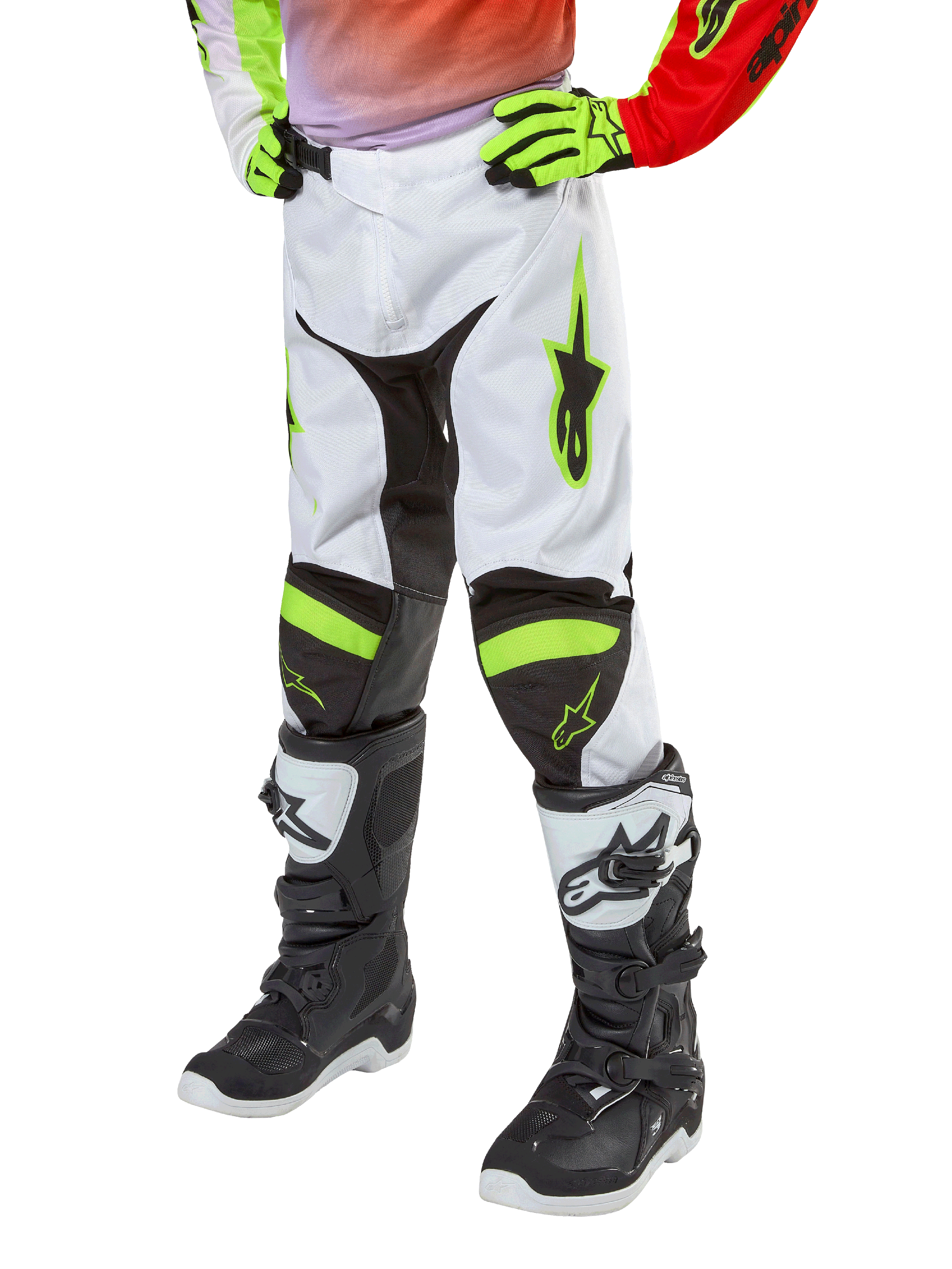 Alpinestars Youth 2024 Racer Lucent byxor, motocrossbyxor, vita med neonröda och neongula detaljer, underkroppsvy med svarta stretchpaneler och neonaccenter, bärs med svarta och vita racingstövlar och neongula handskar, teknisk offroad-utrustning för ungdom
