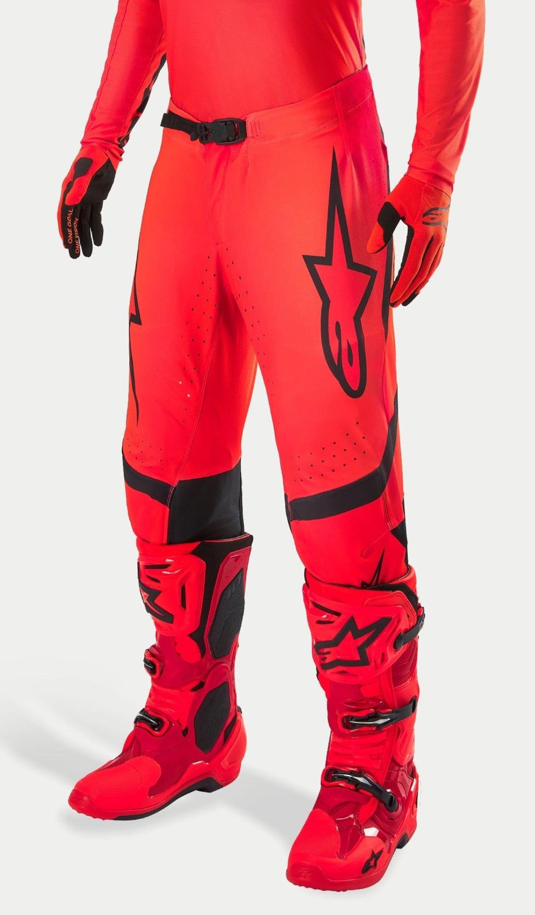 Alpinestars Supertech Ember LE motocrossbyxor, fluorescerande röd och klar röd med svarta detaljer, bärs med matchande röda racingstövlar och handskar, med en framträdande svart stjärnlogotyp på benet, säkert midjespänne och perforerade zoner för ventilation.