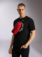 Alpinestars Only Linear midjeväska i rött och svart, bärs cross-body över en svart grafisk t-shirt, med en tydlig svart Alpinestars-logotyp och ett justerbart webbingband för en urban casual look