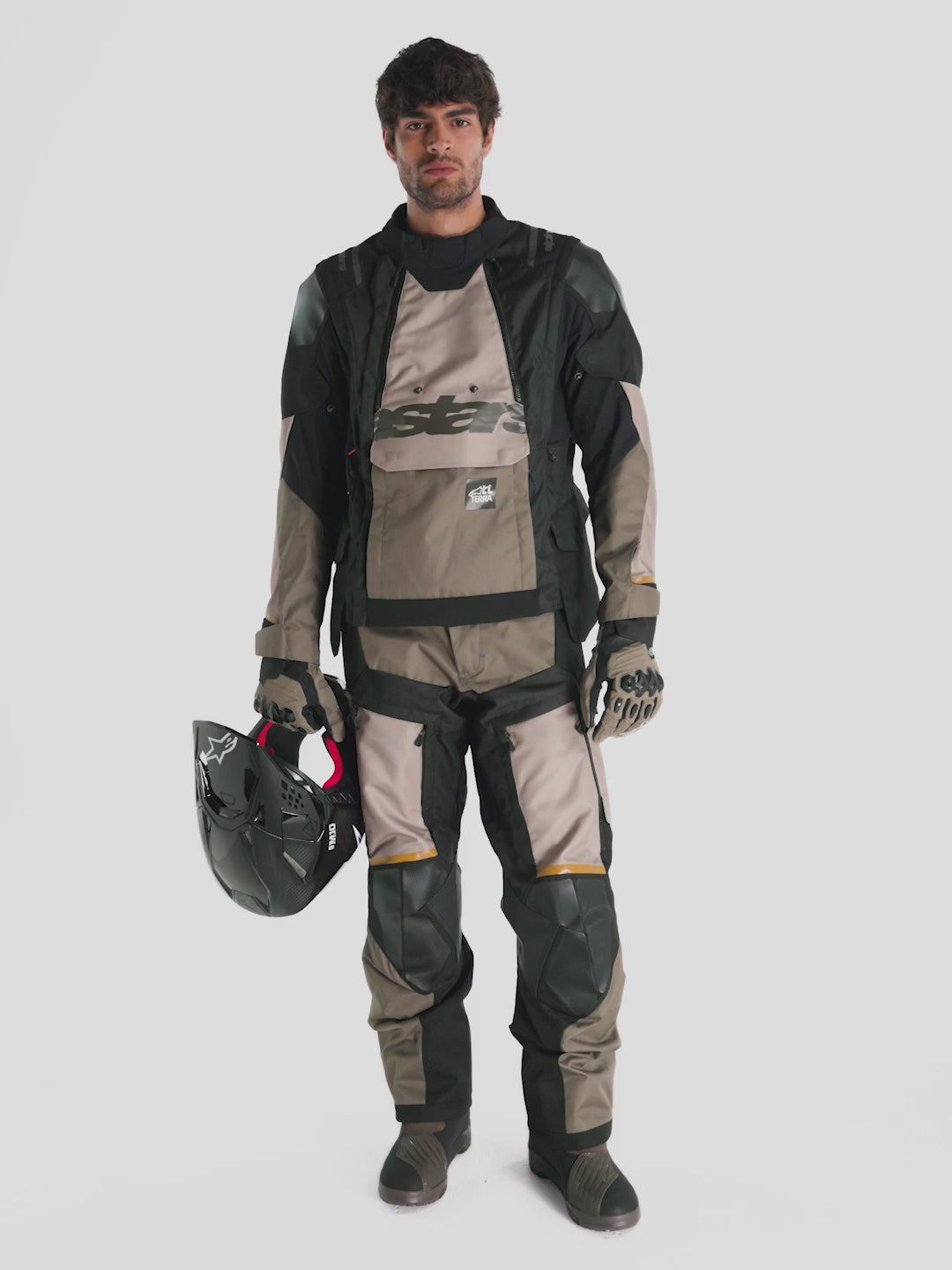 Alpinestars Harok V2 Drystar Jacket, men's adventure touring motorcycle jacket in aluminum, walnut, and black, full-body view of a model wearing matching textile gear and helmet holding off-road gloves.